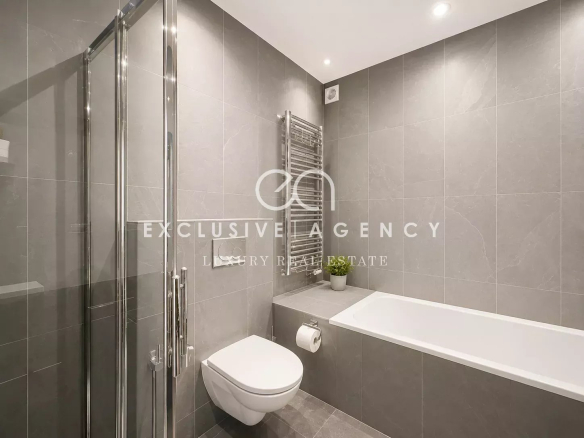 Salle de bains moderne avec douche et baignoire, carrelage gris.