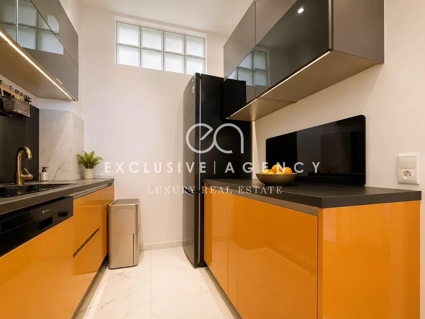 Cuisine d’un appartement à Cannes Cuisine moderne avec des meubles noirs et orange, éclairage naturel, dans un appartement à Cannes.