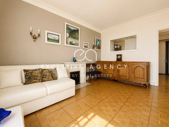 Salon lumineux d'un appartement à Cannes avec un canapé blanc et des œuvres d'art au mur.