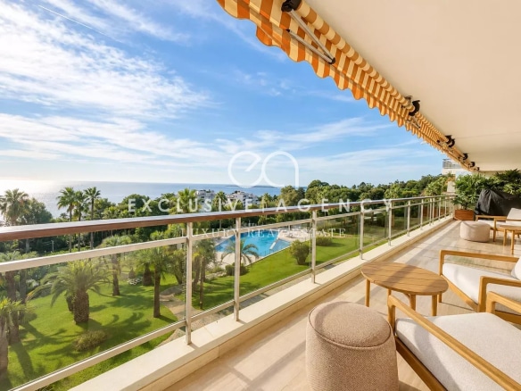 Terrasse d'un appartement avec vue sur la mer et piscine, entourée de palmiers à Cannes.