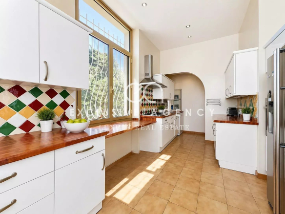 Spacious and bright kitchen in a villa in Cannes, with white cabinets and a wooden worktop.