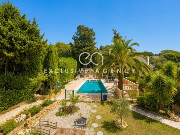View of the pool and garden of a villa in Cannes, with trees and plants around.