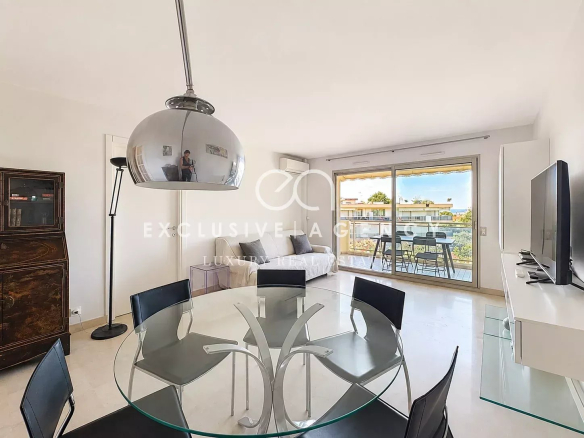 Intérieur d'un appartement lumineux à Cannes avec salon, salle à manger et accès à une terrasse.