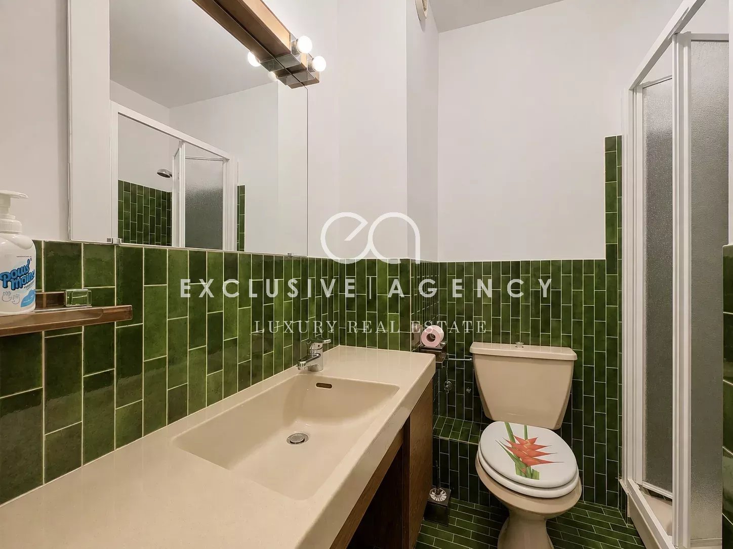 Salle de bains d’un appartement à Cannes Salle de bains avec carrelage vert, lavabo et toilettes dans un appartement à Cannes.