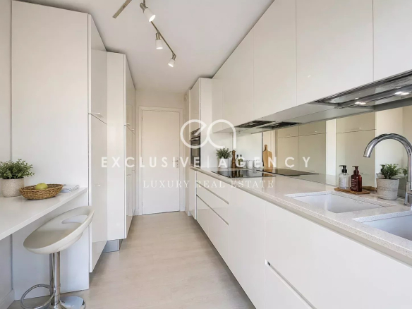 Cuisine moderne et lumineuse d'un appartement à Cannes, avec meubles blancs et bar.