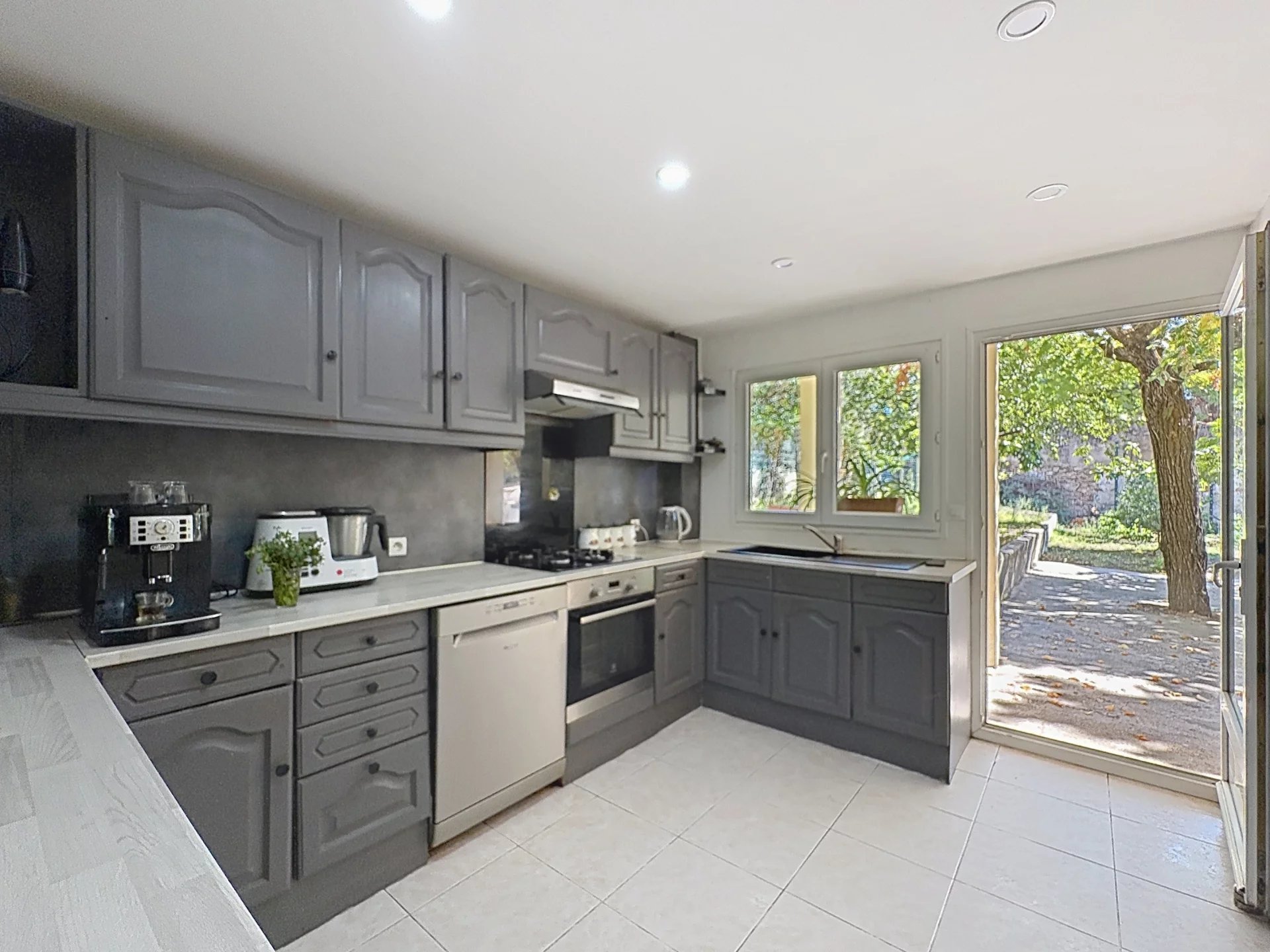 Family home cooking in Cannes Modern kitchen with grey furniture and access to the outside, in a house in Cannes.