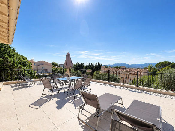Spacious terrace of a house in Cannes with sun loungers and unobstructed views of the greenery.