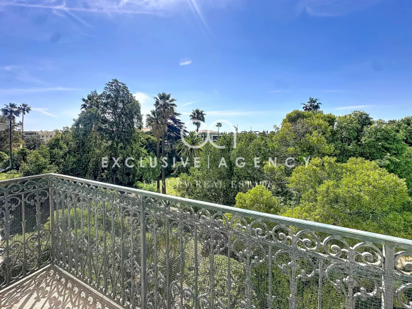 Vue depuis la terrasse d'un appartement à Cannes, entourée d'arbres et de verdure.