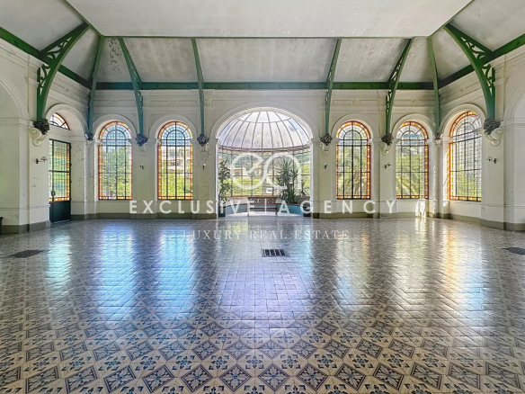 Intérieur d'un grand espace lumineux avec des fenêtres en arc et un sol carrelé décoratif.