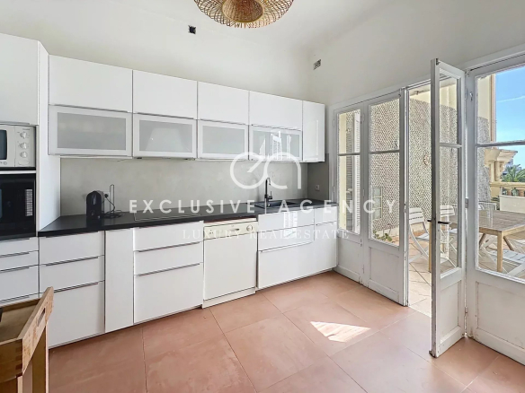 Cuisine moderne d'un appartement à Cannes avec meubles blancs et accès à une terrasse.
