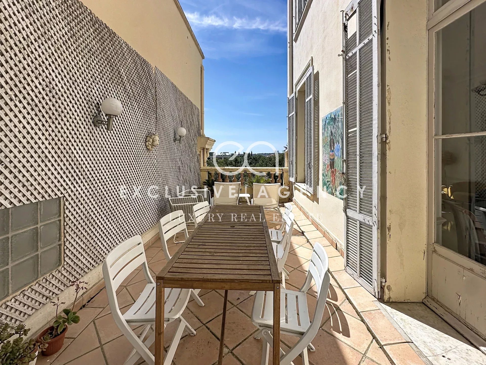 Terrasse d’appartement à Cannes Terrasse d'un appartement à Cannes avec table en bois et chaises blanches.