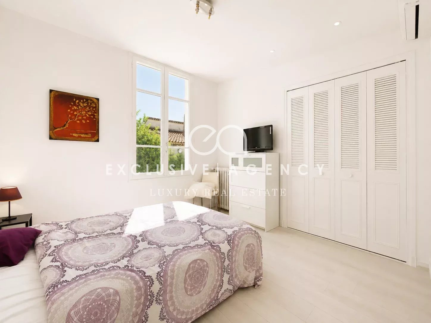 Chambre de villa à Cannes Chambre d'une villa à Cannes avec lit, télévision et fenêtres laissant entrer la lumière.