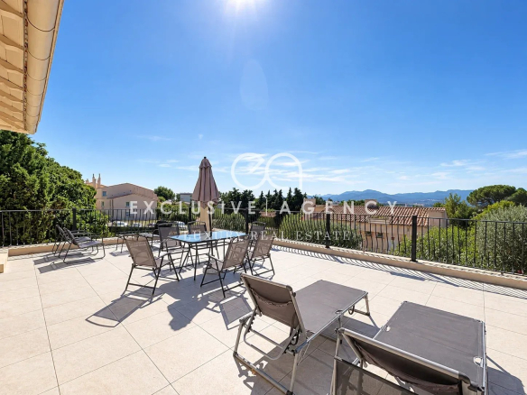 Spacious terrace with sun loungers and table, unobstructed view of the hills in Cannes.