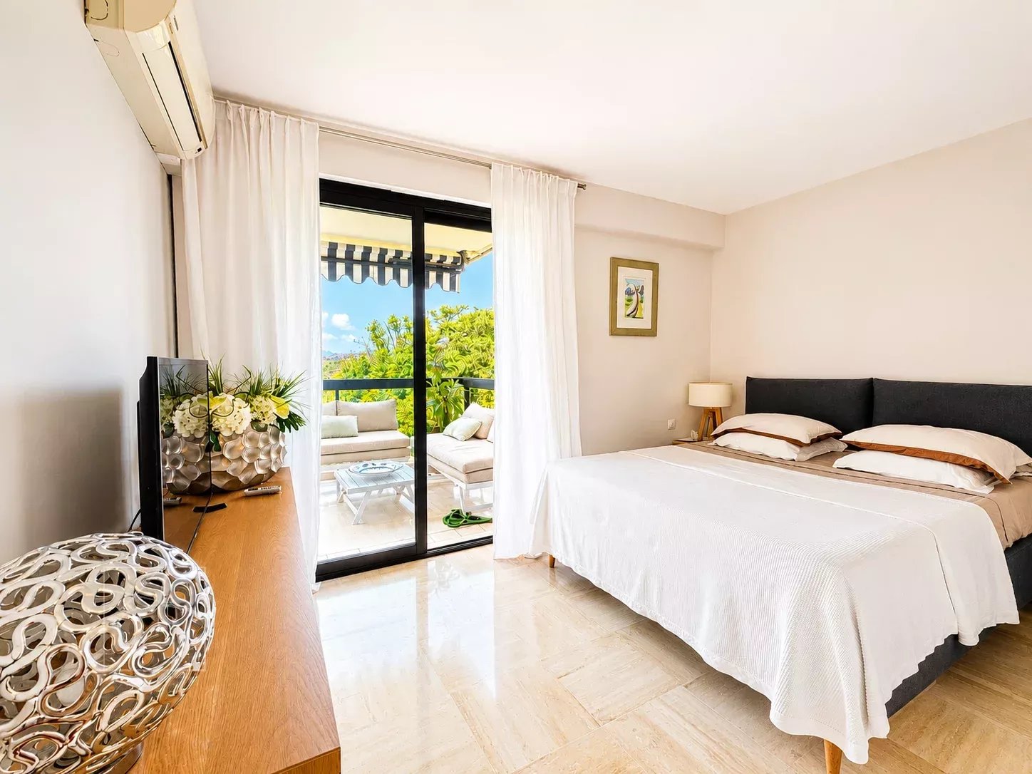 Chambre d'un appartement rénové à Cannes avec vue sur le jardin et accès à une terrasse.