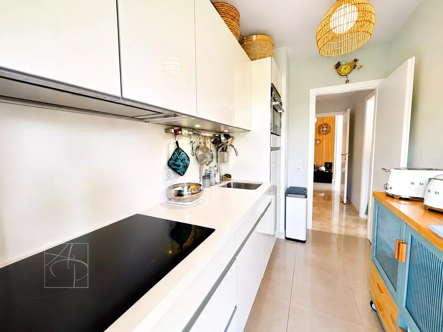Cuisine moderne d'un appartement rénové à Cannes avec plans de travail clairs et rangement.