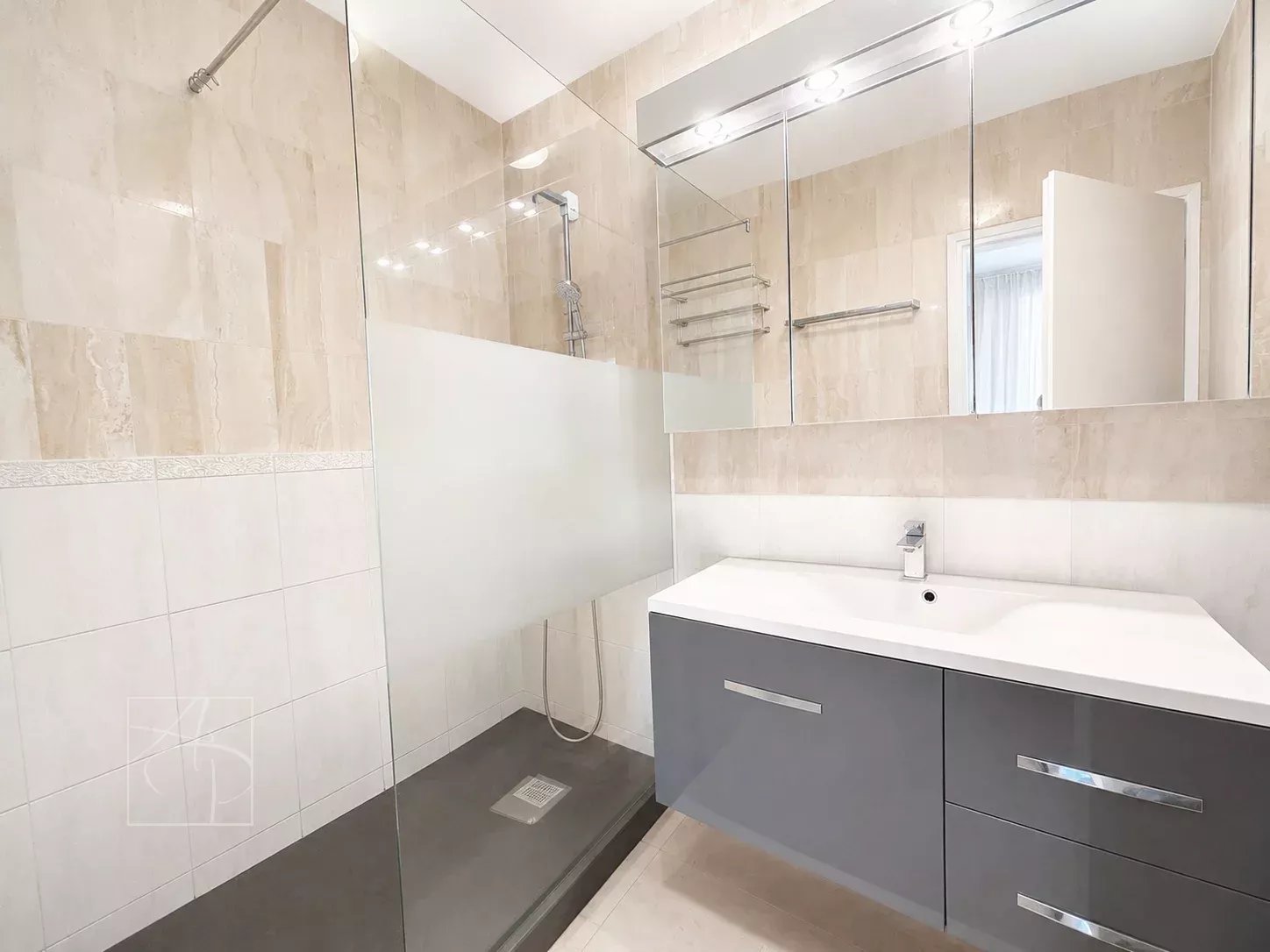Salle de bain moderne avec douche à l'italienne et meuble vasque dans un appartement à Cannes.