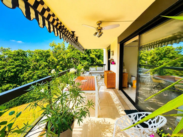 Terrasse spacieuse d'un appartement à Cannes avec vue sur jardins et aperçu mer.