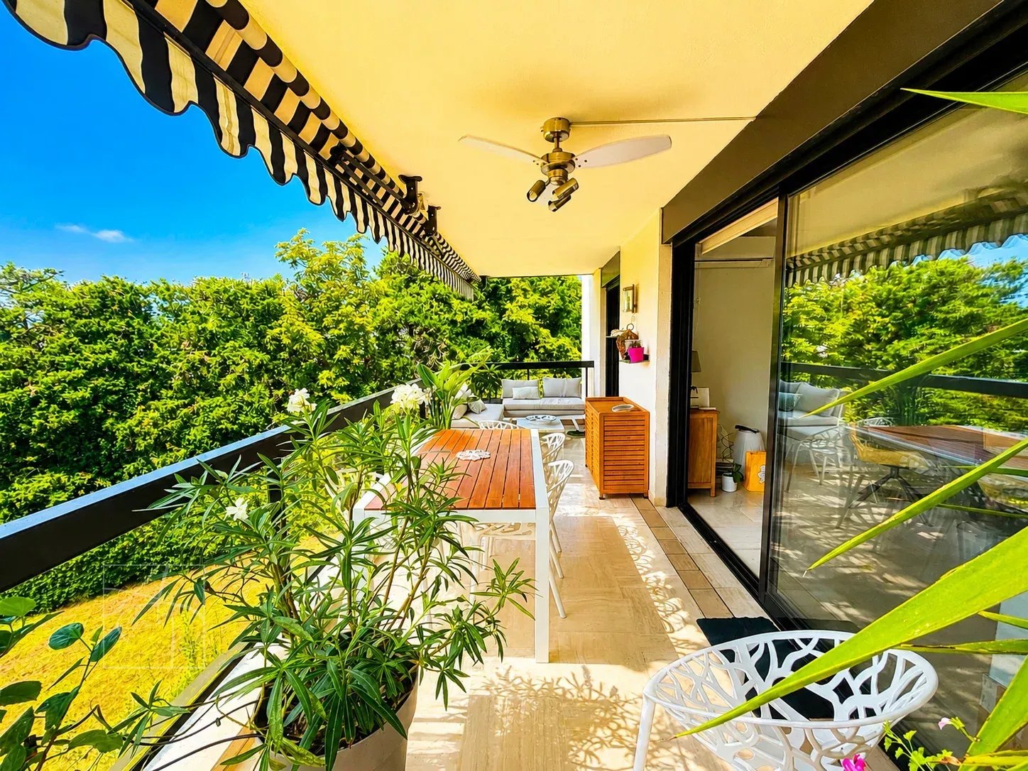 Terrasse spacieuse d'un appartement à Cannes avec vue sur jardins et aperçu mer.