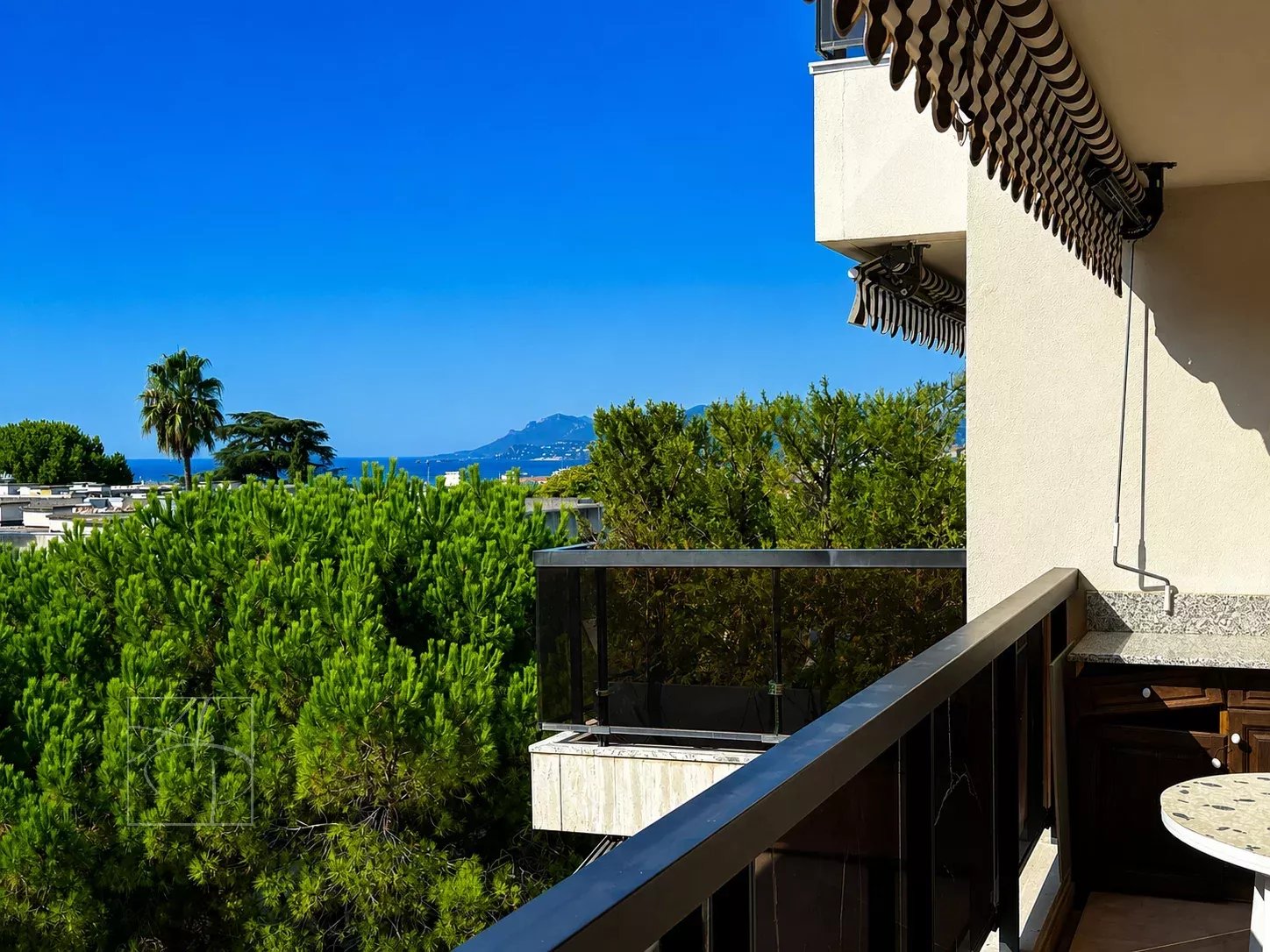 Unobstructed view from the balcony of a top-floor apartment in Cannes, with sea and greenery in the background.