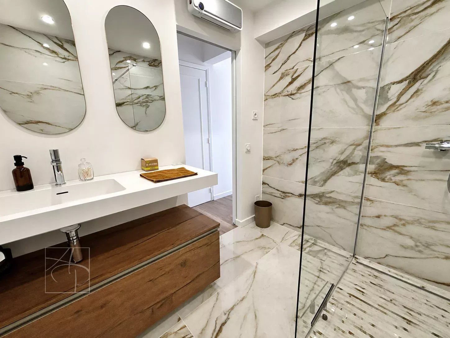 Salle de bain moderne avec douche en verre et meuble en bois, murs en marbre