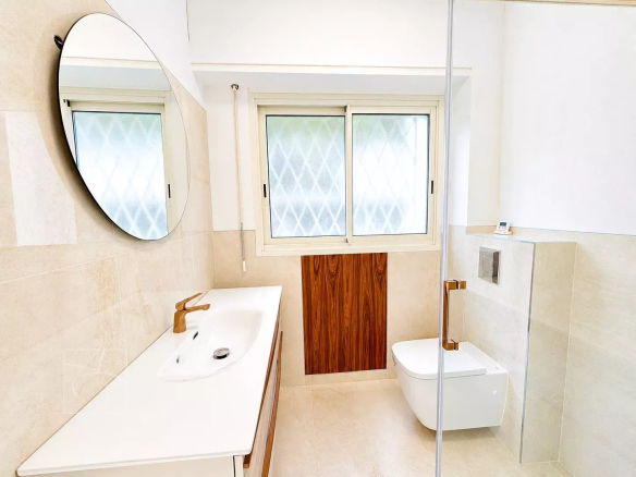 Modern bathroom with sink and toilet, window letting in light.