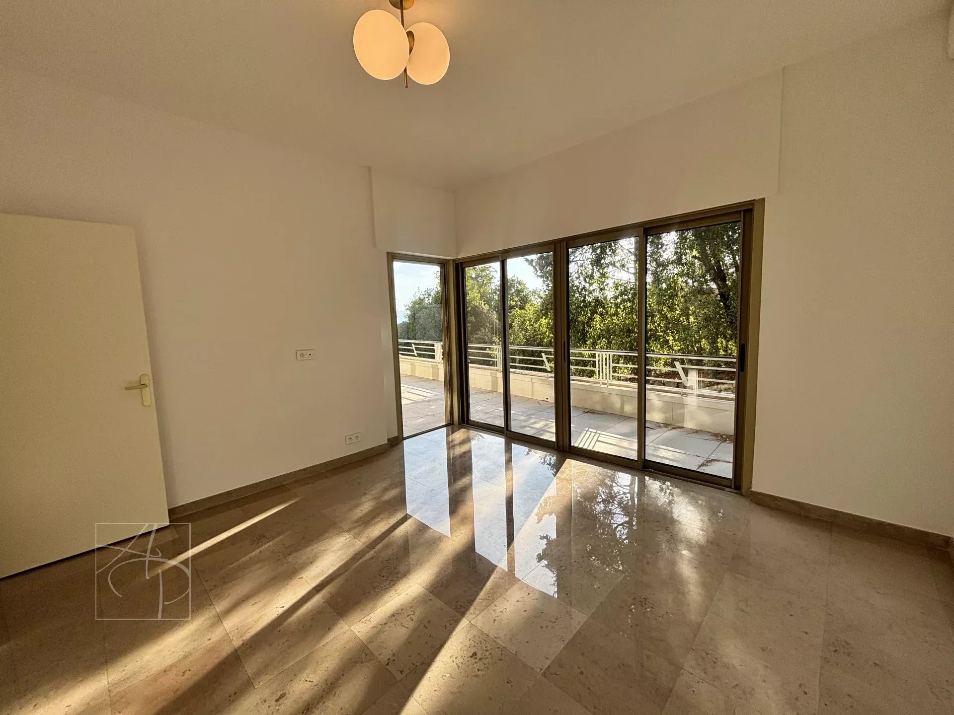 Interior of a bright apartment with large windows and marble floor in Cannes.