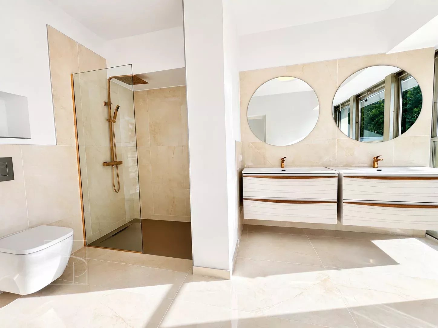 Modern bathroom with shower, double sink and large windows letting in light.