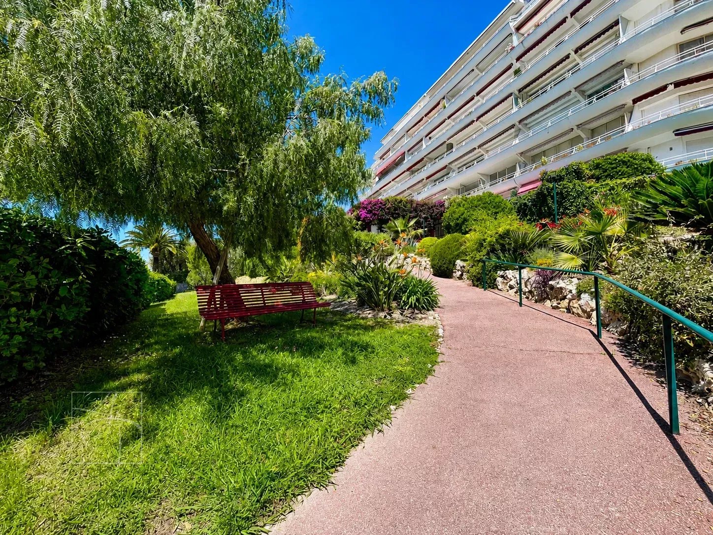 Chemin menant à un bâtiment résidentiel entouré de verdure à Cannes Montfleury.