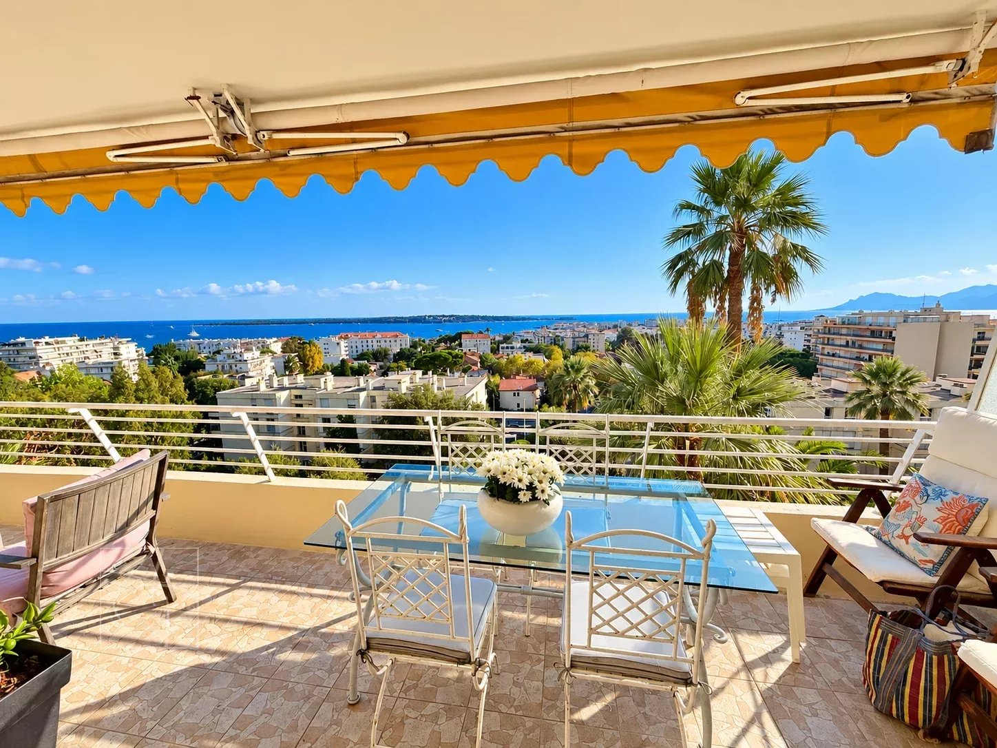 Vue mer depuis la terrasse d’un appartement à Cannes Terrasse avec vue panoramique sur la mer et les îles de Lérins à Cannes, avec mobilier de jardin.