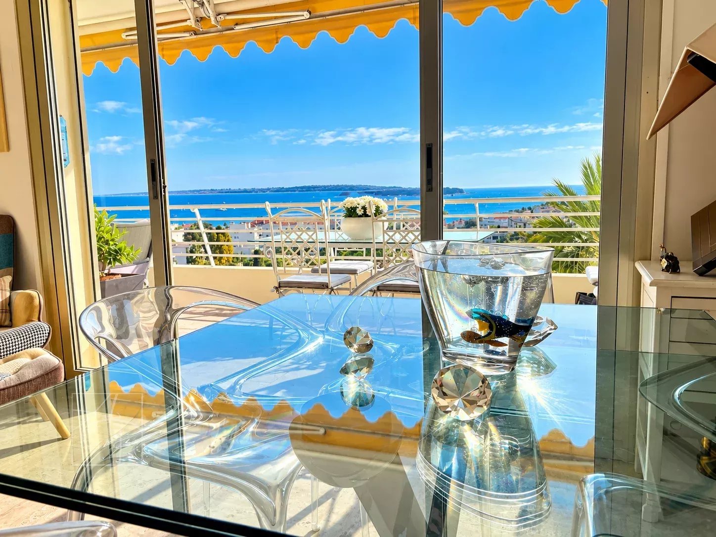 Vue mer depuis un appartement à Cannes Vue panoramique sur la mer depuis un appartement à Cannes, avec une table en verre et des décorations.