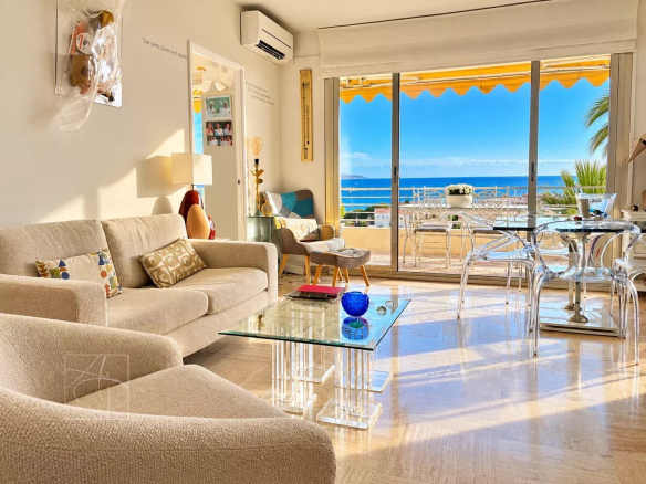 Intérieur d'un appartement lumineux avec vue mer à Cannes, salon moderne et terrasse ensoleillée.