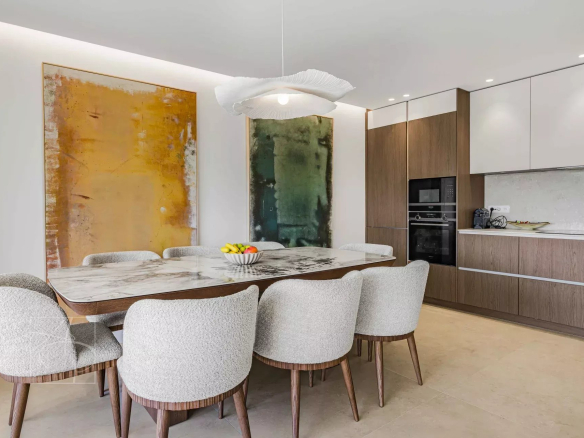 Dining room of a renovated apartment with a large table and comfortable chairs.