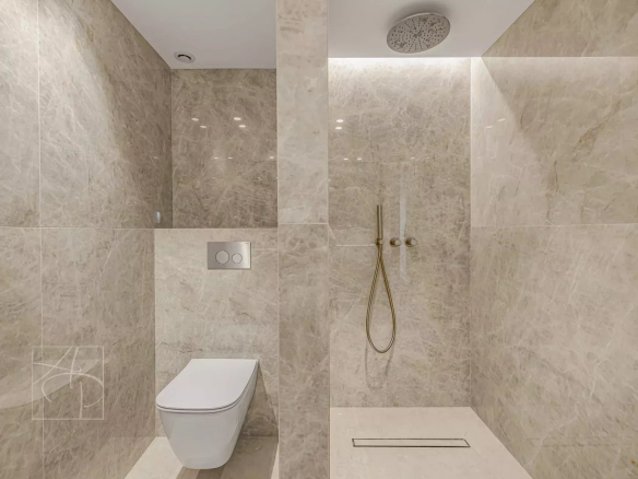 Modern bathroom with shower and toilet, clad in marble.
