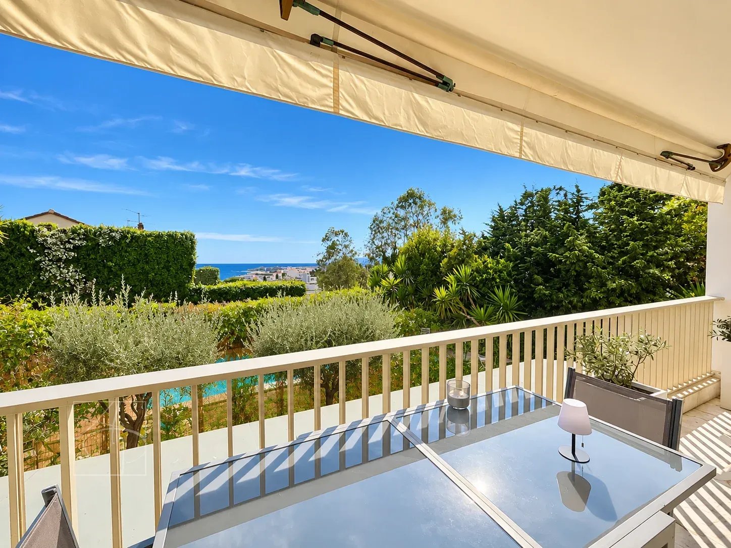 Terrasse d'un appartement à Cannes avec vue sur la mer et jardin verdoyant.