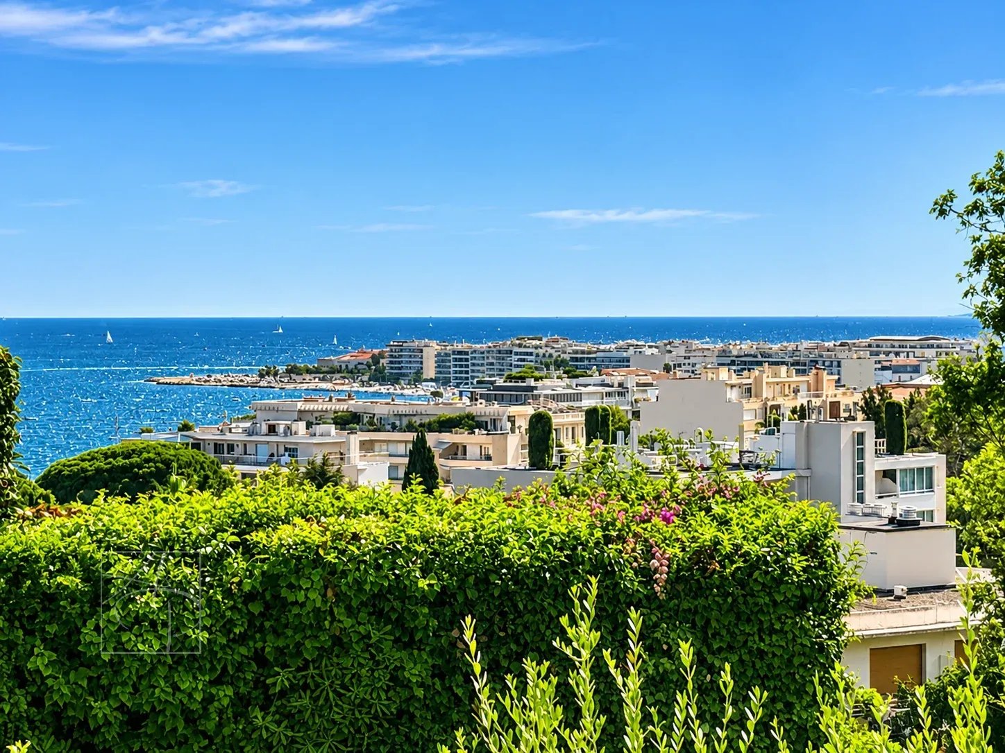 Vue dégagée sur la mer depuis un appartement à Cannes, entouré de verdure.