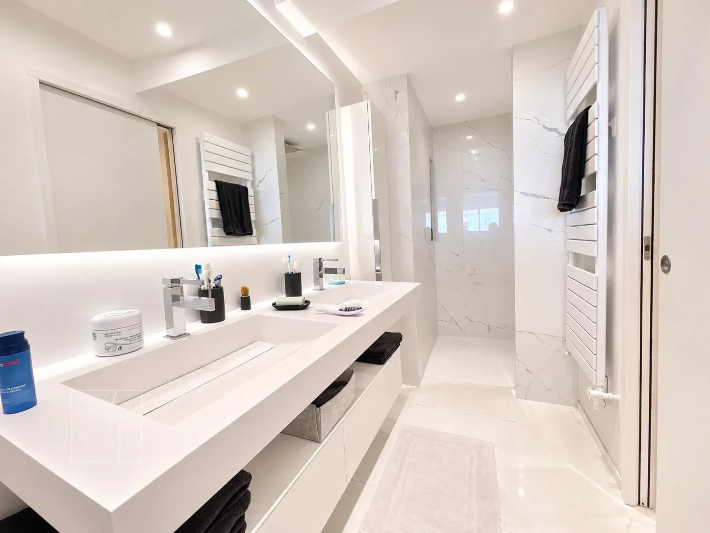 Salle de bain moderne et rénovée avec douche et double vasque.