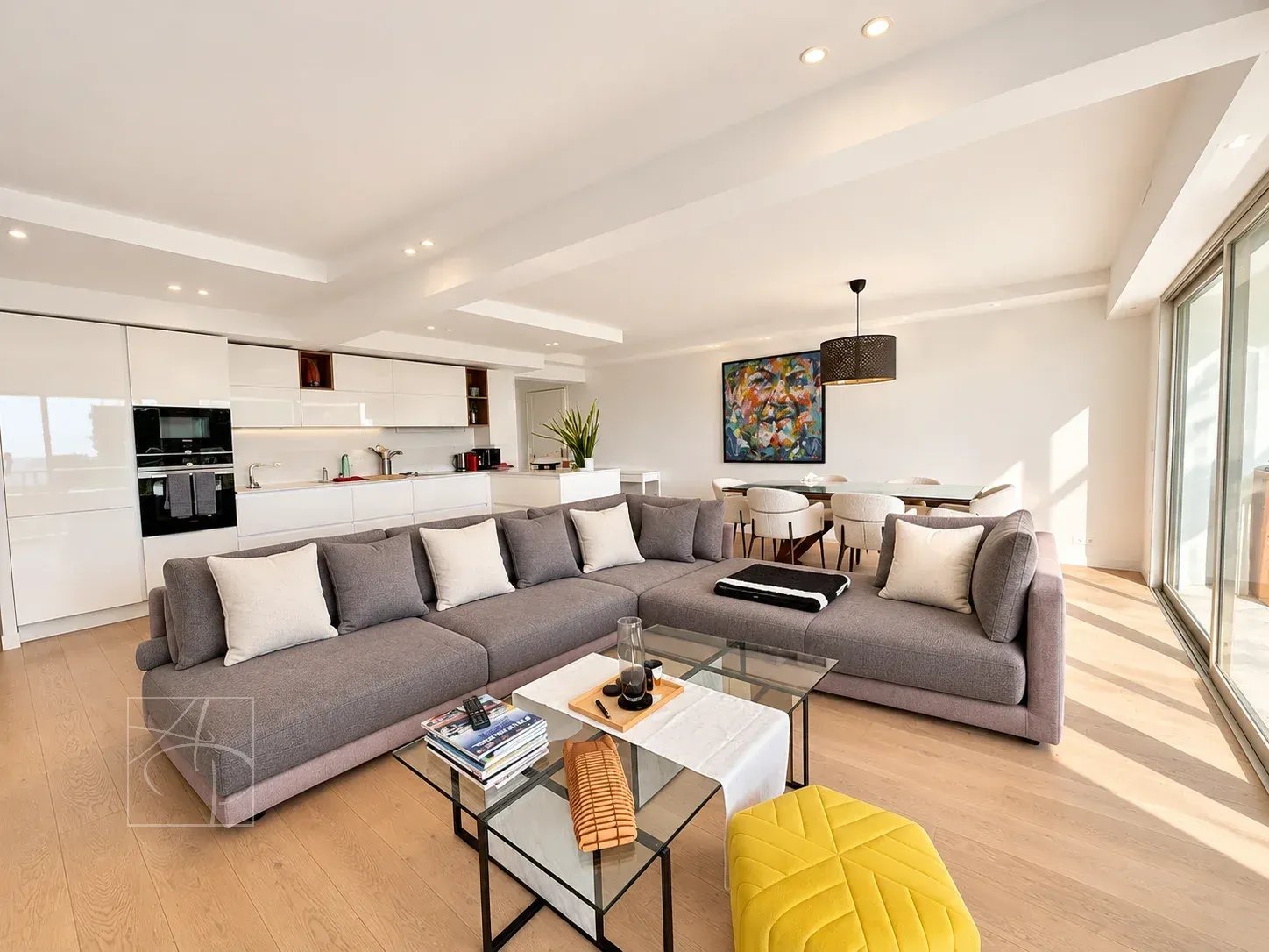 Salon lumineux d'un appartement rénové avec vue sur la mer à Cannes, mobilier moderne et espace ouvert.