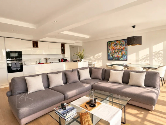 Salon moderne d'un appartement rénové avec canapé et cuisine ouverte.