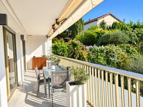 Terrasse d'un appartement rénové à Cannes avec vue sur des jardins fleuris.