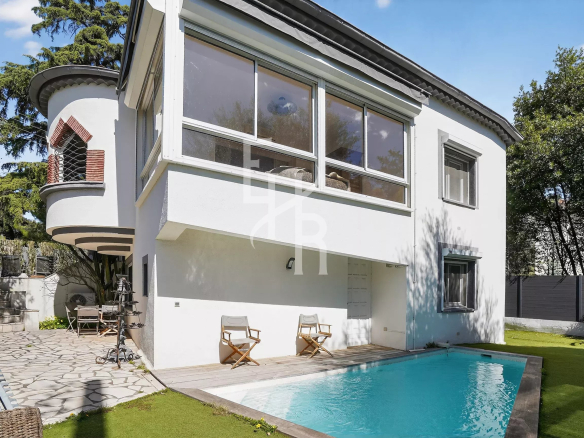 White modern two-story house with large bay windows and a rectangular pool in the yard