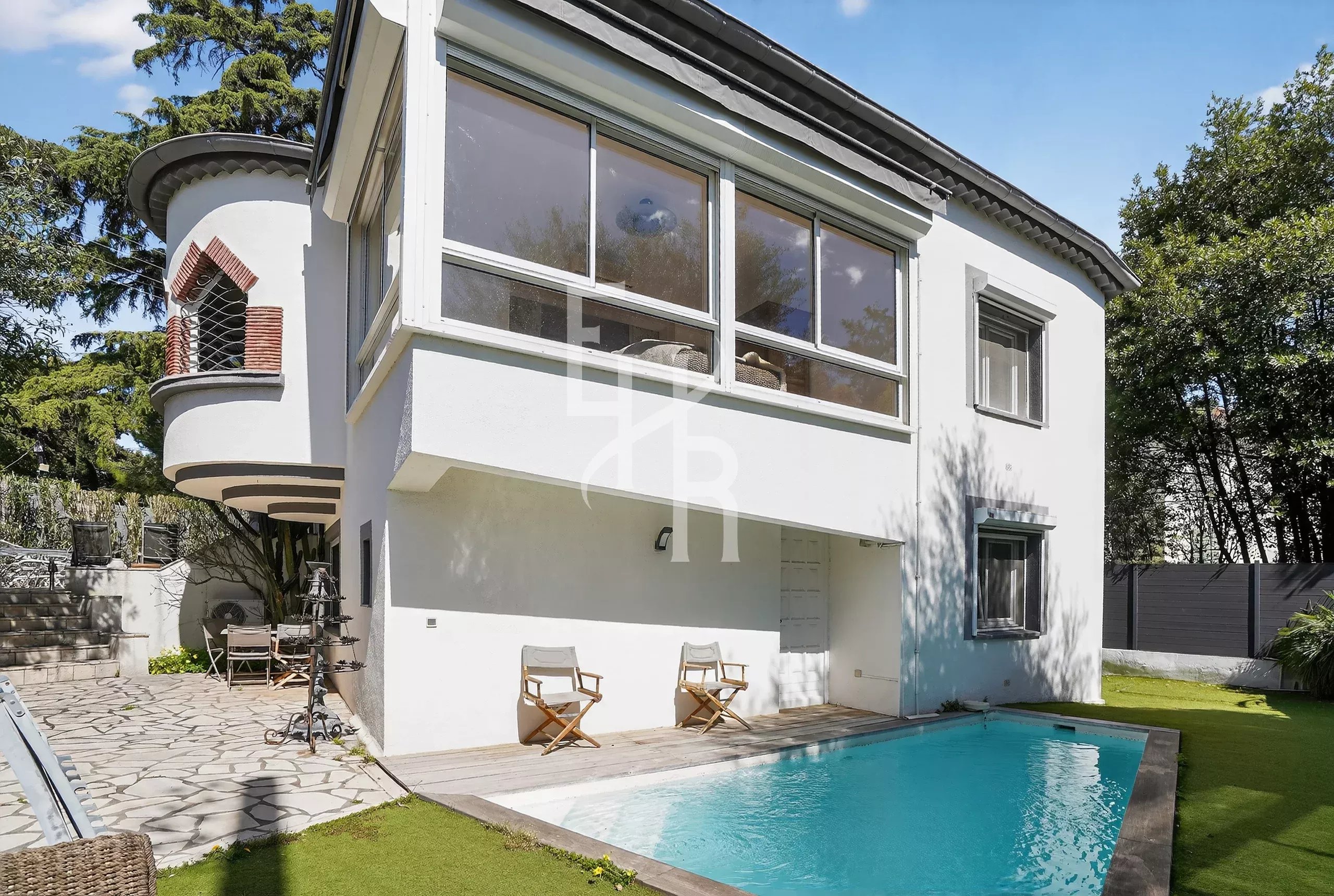 White modern two-story house with large bay windows and a rectangular pool in the yard