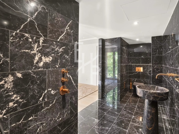 Salle de bain moderne avec des murs en marbre noir et des accessoires dorés
