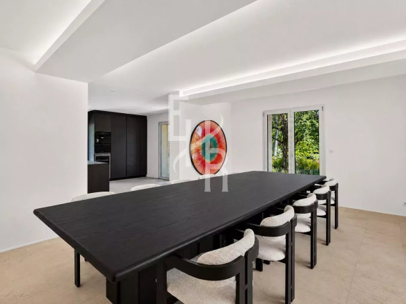 Salle à manger moderne avec une grande table noire et des chaises claires, donnant sur un jardin.