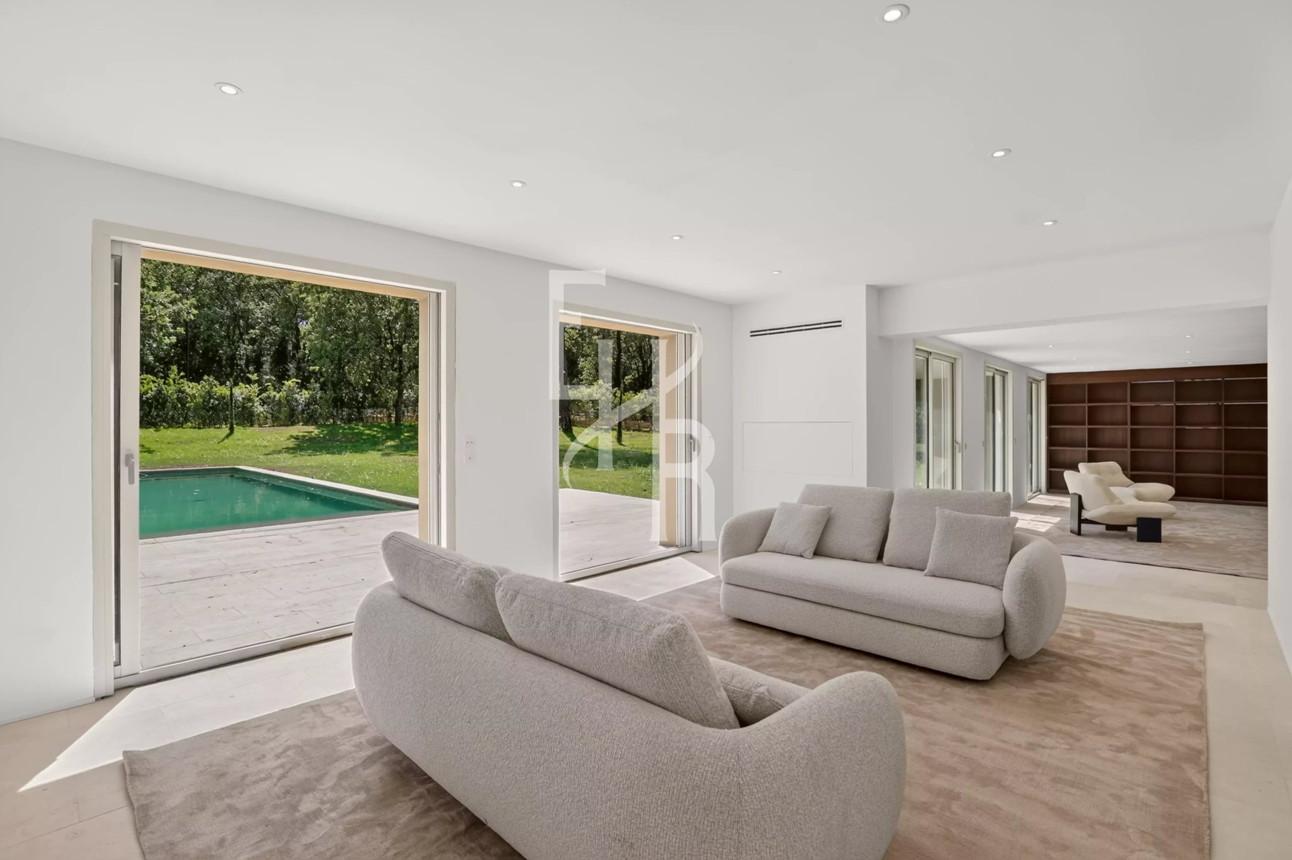 Intérieur de la villa à Mougins Intérieur moderne d'une villa à Mougins avec salon et vue sur la piscine extérieure
