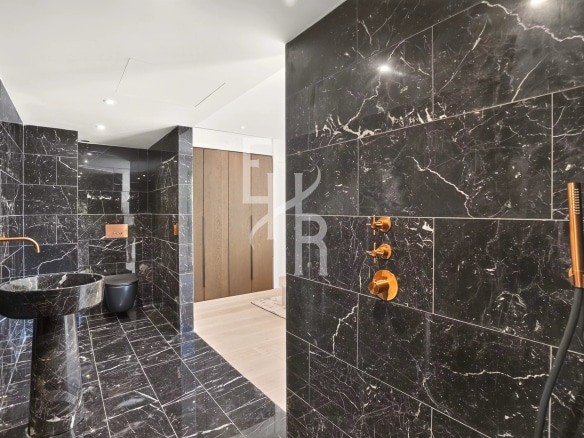 Salle de bain moderne avec des murs en marbre noir et des accessoires dorés.