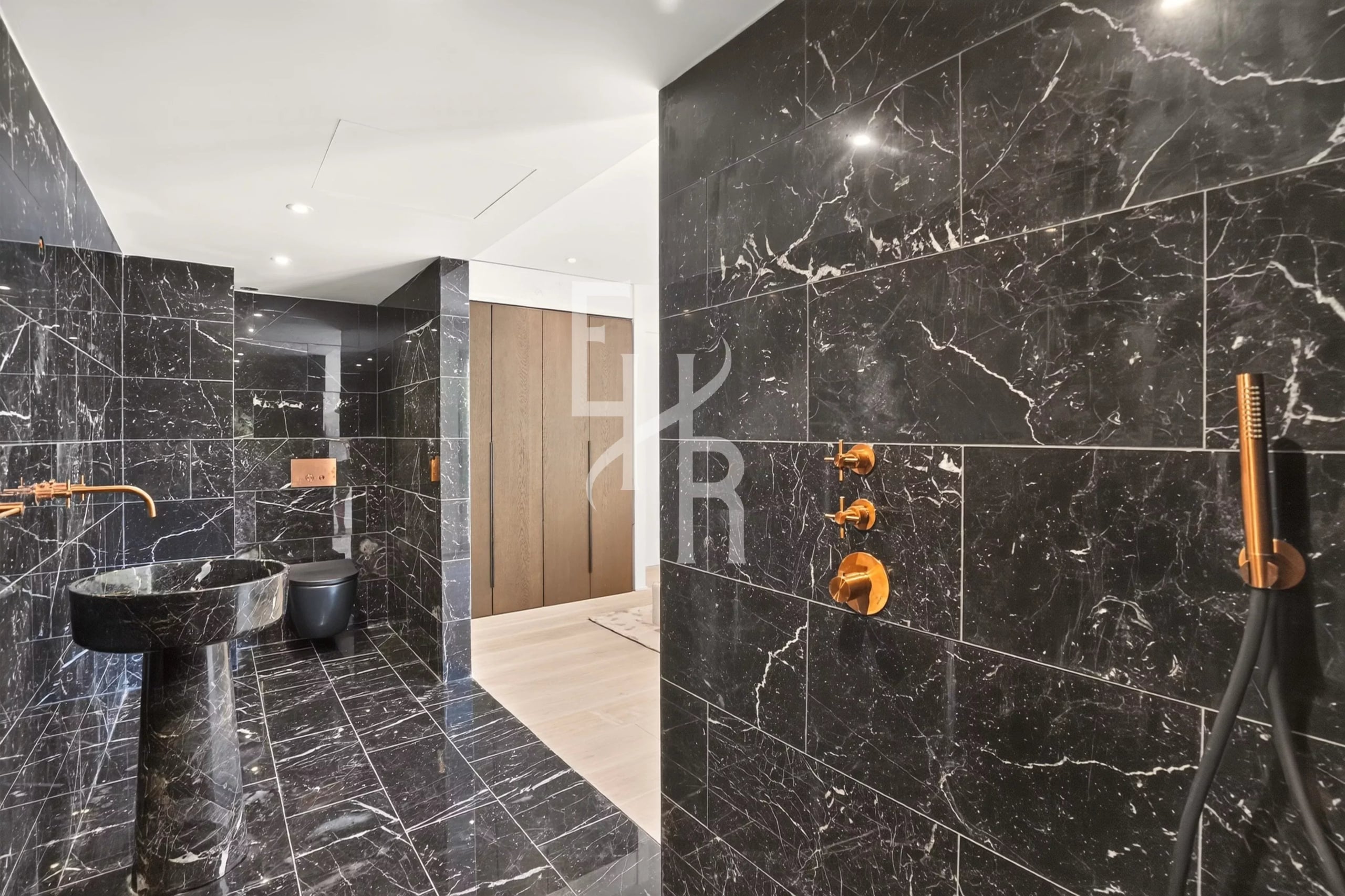 Salle de bain élégante à Mougins Salle de bain moderne avec des murs en marbre noir et des accessoires dorés.