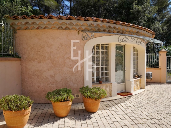 Entrance to a villa in Cabris with flower pots and a stone wall.