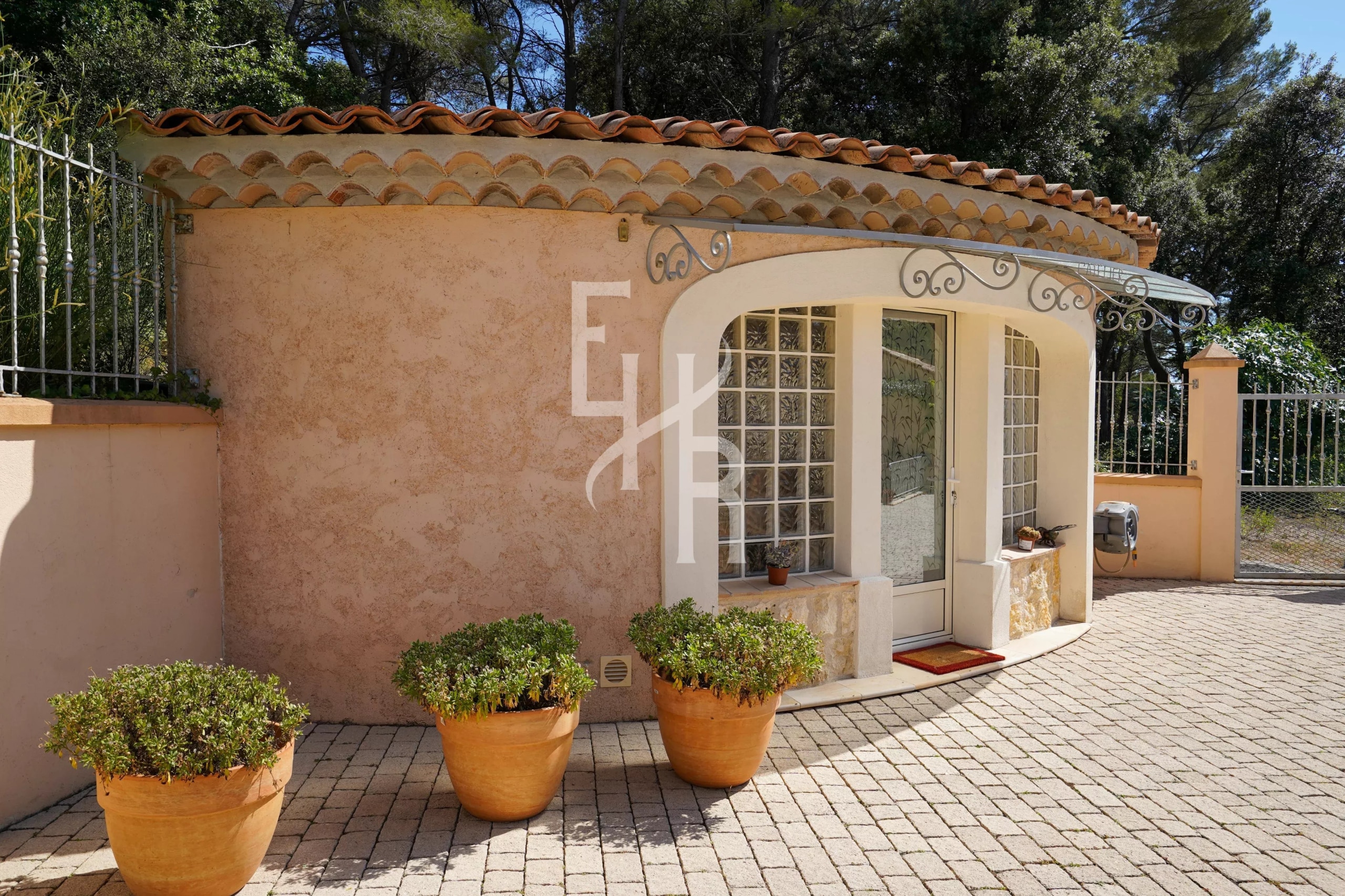 Entrance to a villa in Cabris with flower pots and a stone wall.