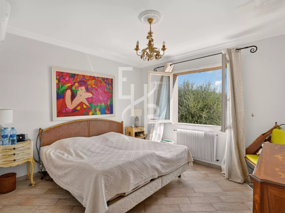 Chambre d'une villa familiale à Opio avec lit, tableau coloré et fenêtre donnant sur l'extérieur.