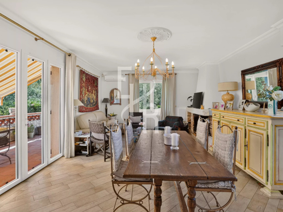 Intérieur d'une villa familiale avec salle à manger, cheminée et accès à une terrasse.
